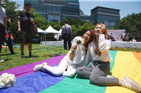 Kristin Wang, left, and Amber Wang, right, gesture on a rainbow blanket in Taipei.