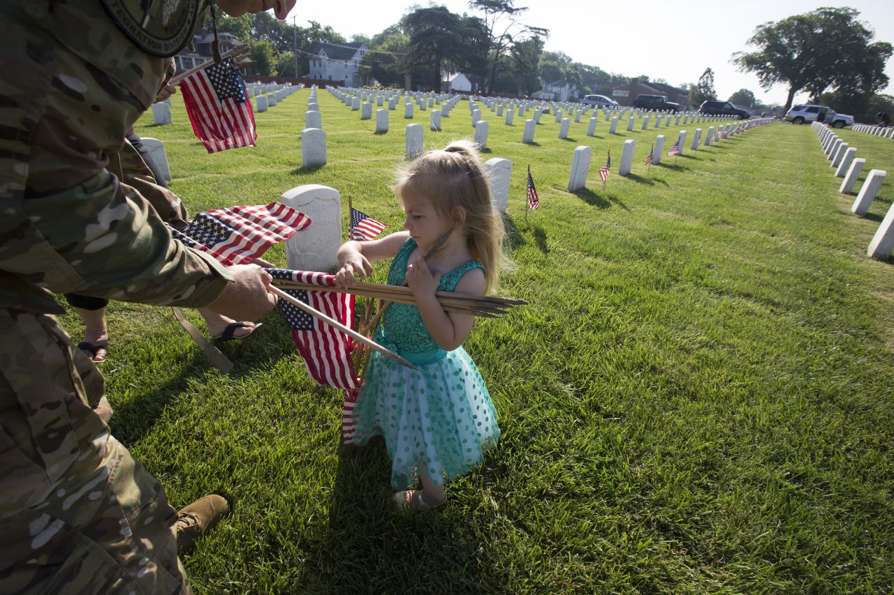 Samara Reisenweber helps her father, Air Force Lt. Col. Andrew Reisenweber, place flags at graves at Hampton National Cemetery in Virginia on May 24.