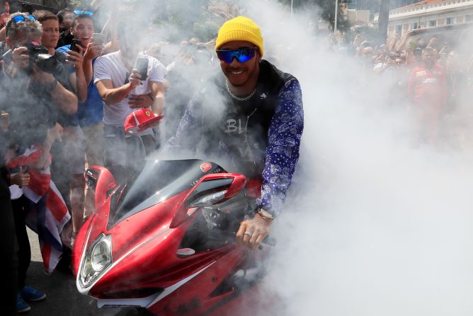 Mercedes driver Lewis Hamilton smiles on a motorbike in the fan zone at the Monaco Grand Prix in Monte Carlo on Friday, May 24.