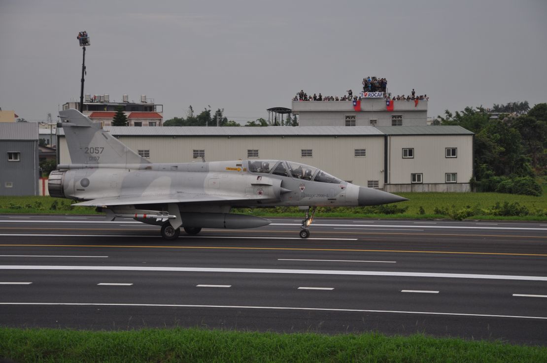 A Taiwan Mirage 2000 jet prepares to take off on a highway, during an exercise outside Taichung on Tuesday. In the background, onlookers wave the Taiwan flag.