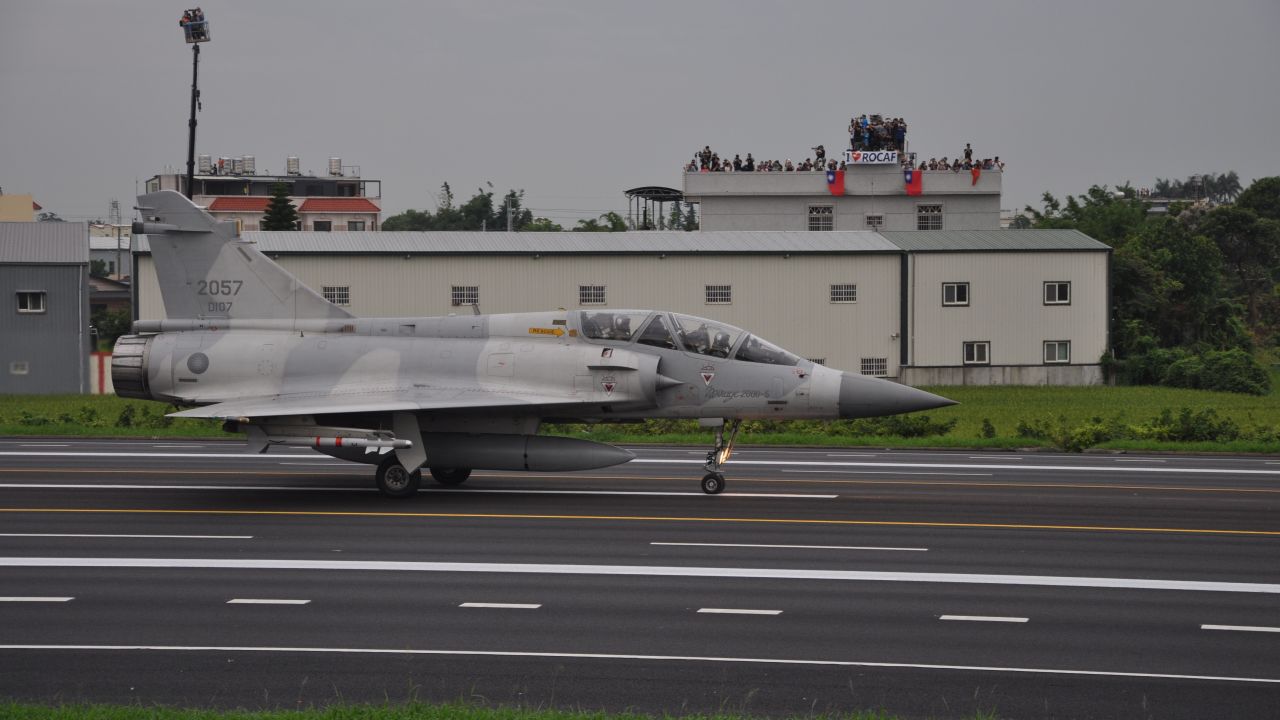 A Taiwan Mirage 2000 jet prepares to take off on a highway, during an exercise outside Taichung on Tuesday. In the background, onlookers wave the Taiwan flag.