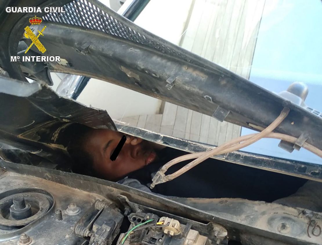 An African migrant squeezed inside a compartment built behind a car dashboard.