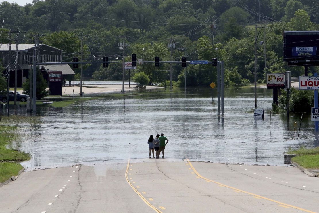 People peer out over the flooded Massard Creek from the middle of a road in Fort Smith, Arkansas.