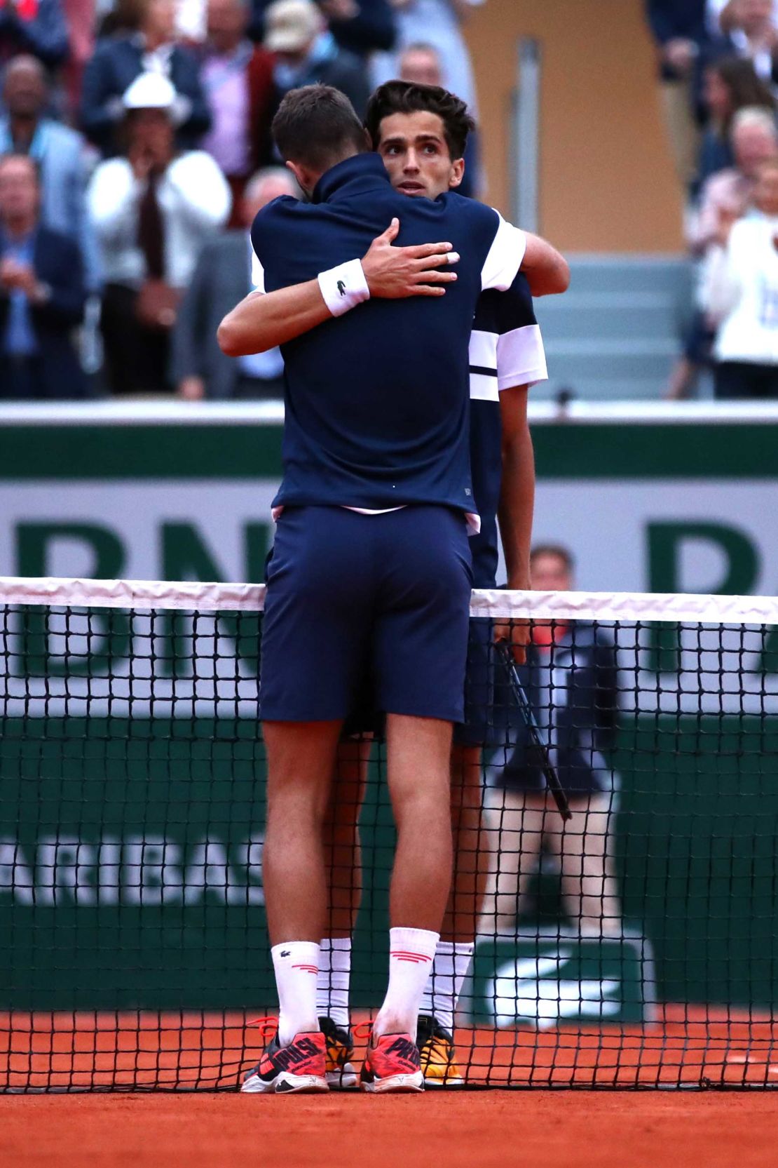 Pierre Hugues-Herbert (facing camera) and Benoit Paire embrace after their battle at the French Open. 