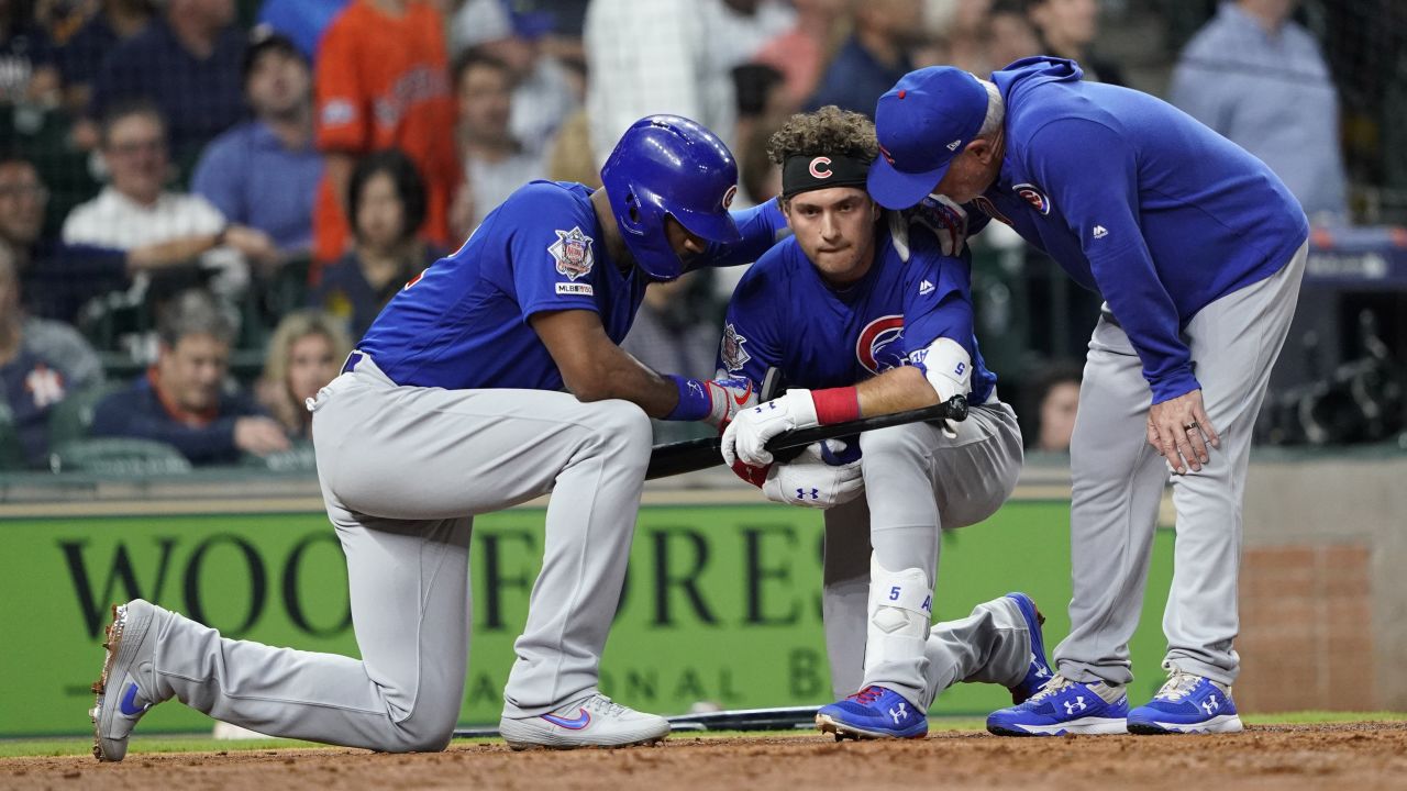 A distraught Chicago Cubs' Albert Almora Jr., center, kneels as Jason Heyward, left, and manager Joe Maddon, right, talk to him after a foul ball Almora hit into the stands during the fourth inning of a baseball game against the Houston Astros hit a child.