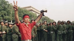 A student pro-democracy protester flashes victory signs to the crowd as People's Liberation Army troops withdraw on the west side of the Great Hall of the People near Tiananmen Square on Saturday, June 3, 1989 in Beijing. (AP Photo/Mark Avery)