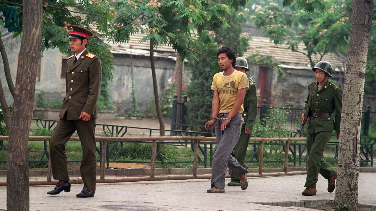A handcuffed man is led by Chinese soldiers on a street in Beijing 14 June, 1989, as police and soldiers keep searching people involved in pro-democracy protests.