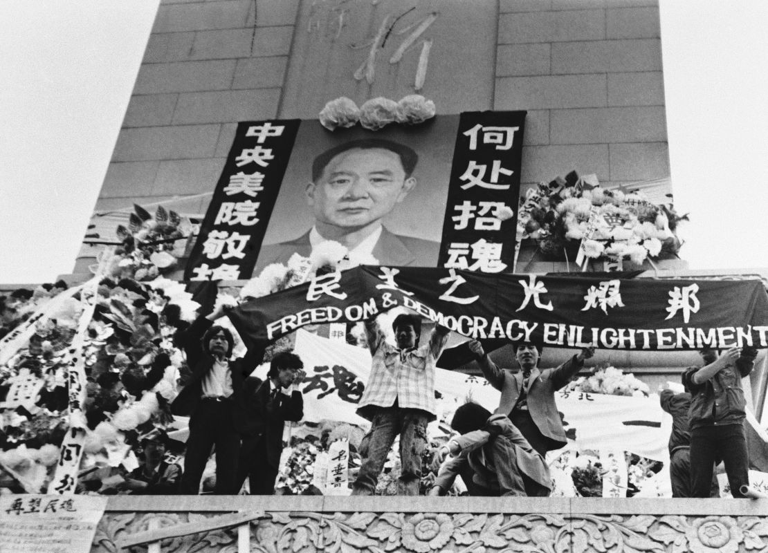 Chinese students hold aloft a banner calling for freedom, democracy and enlightenment on the Martyrs Monument in Beijing's Tiananmen Square, festooned with a giant portrait of Hu Yaobang, April 19, 1989.