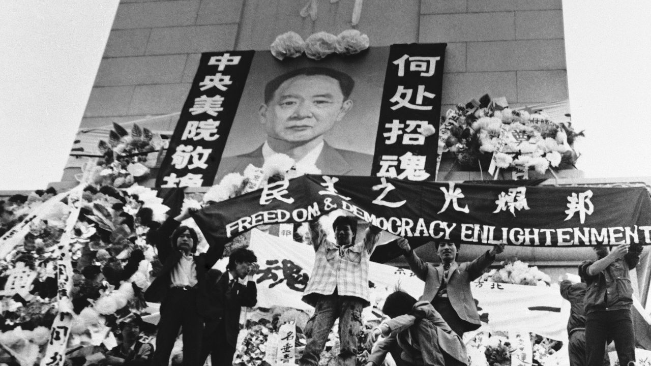 Chinese students hold aloft a banner calling for freedom, democracy and enlightenment on the Martyrs Monument in Beijing's Tiananmen Square, festooned with a giant portrait of Hu Yaobang, April 19, 1989.