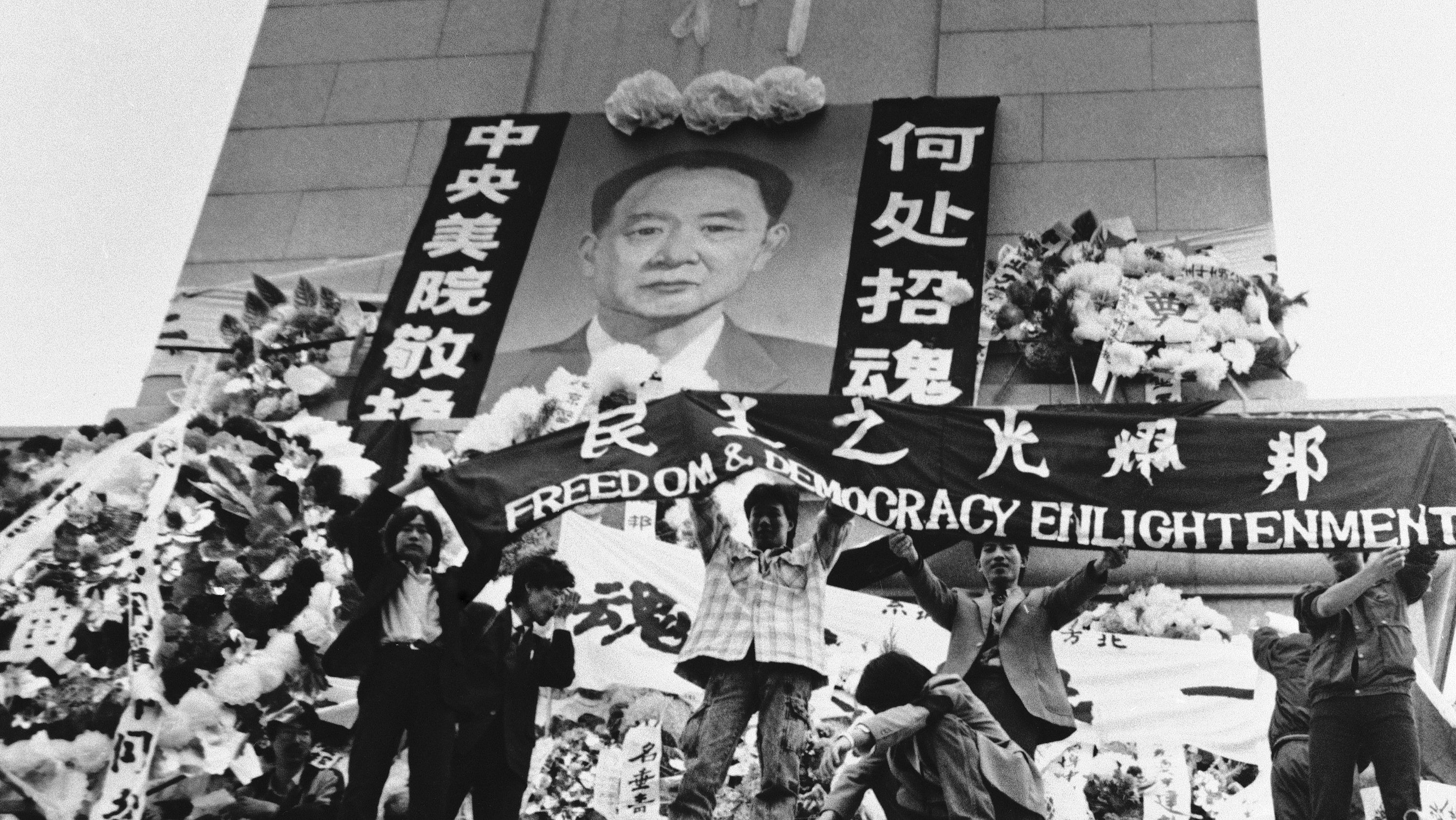 Chinese students hold aloft a banner calling for freedom, democracy and enlightenment on the Martyrs Monument in Beijing's Tiananmen Square, festooned with a giant portrait of Hu Yaobang, April 19, 1989.