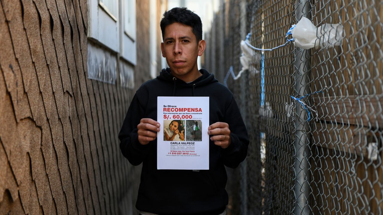 Carlos Jr. holds a reward flyer in the Brooklyn alleyway where he last saw his missing sister in person.