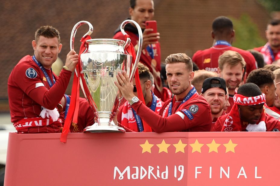 James Milner (L) and Jordan Henderson hold the European Champion Clubs' Cup trophy above an open-top bus at the start of the parade. 