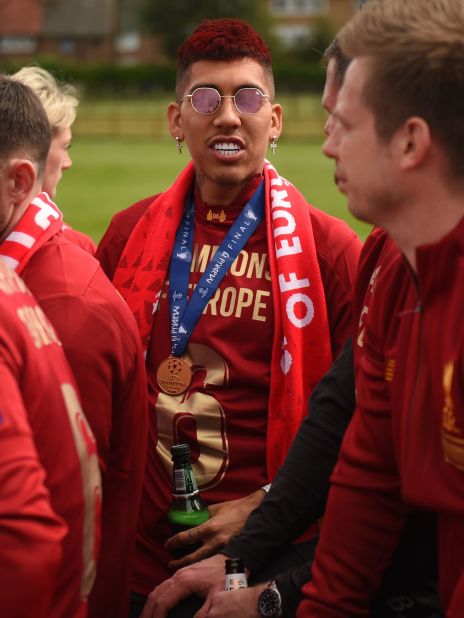 Liverpool's Brazilian midfielder Roberto Firmino shows off his celebratory red hairstyle <br />during an open-top bus parade around the city on Sunday. 