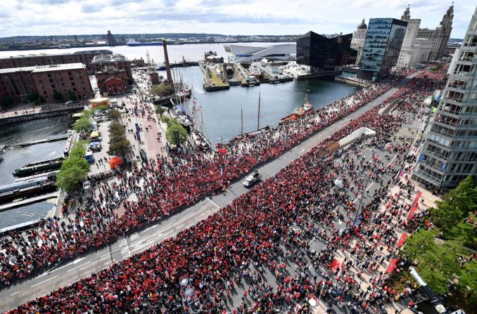 Football fans line the streets waiting to see the Liverpool football team take part in an open-top bus parade around Liverpool on Sunday.