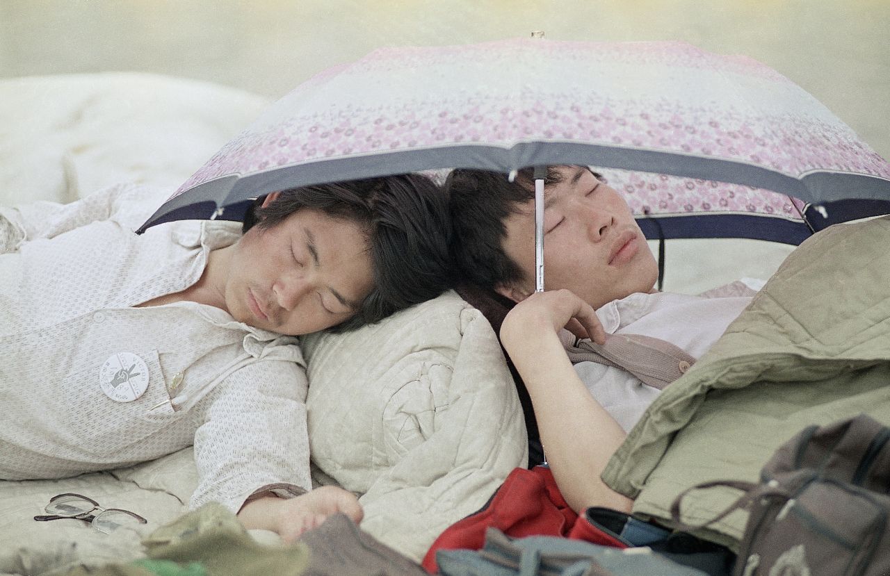 Before "Tank Man," pro-democracy demonstrators had been occupying Tiananmen Square for weeks. Here, university students take a midday break from the protests, using an umbrella to protect them from the heat.