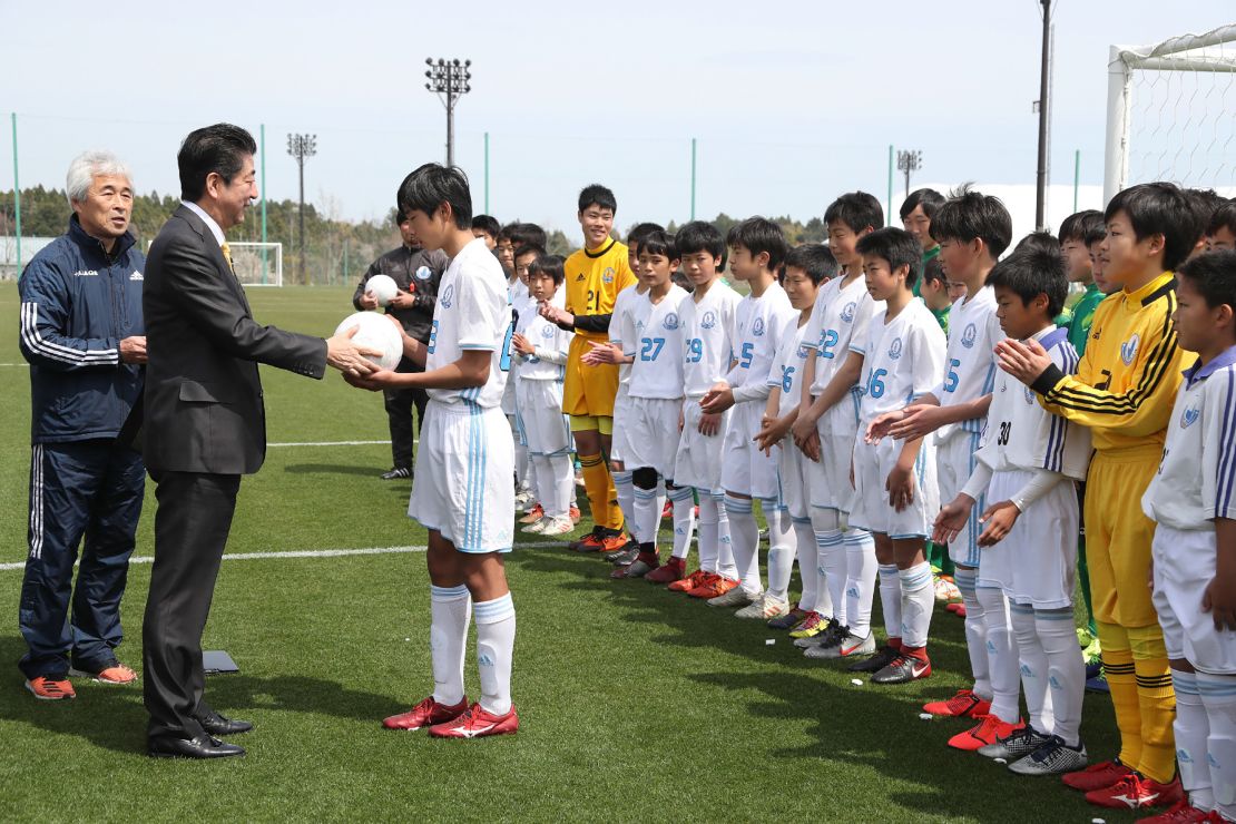 Prime Minister Shinzo Abe presents a ball to a local football club ealier this year when the J-Village was repoened.