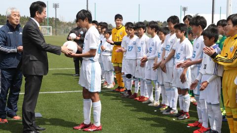 Prime Minister Shinzo Abe presents a ball to a local football club ealier this year when the J-Village was repoened.