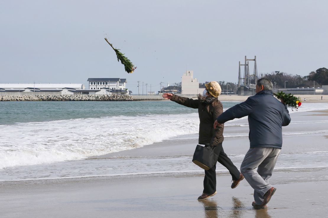 Residents throw bouquets of flowers to mourn those killed in the 2011 tsunami and earthquake.