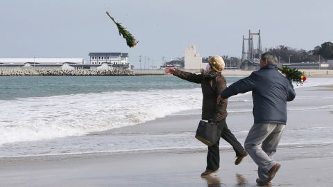Residents throw bouquets of flowers to mourn those killed in the 2011 tsunami and earthquake.