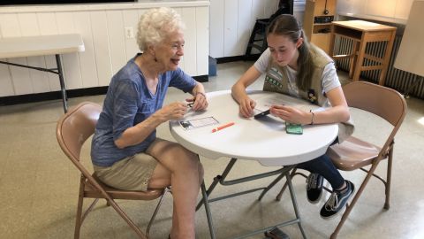 Nancy Taylor consults Girl Scout Cadette Sarah Middleton for advice with her smartphone.