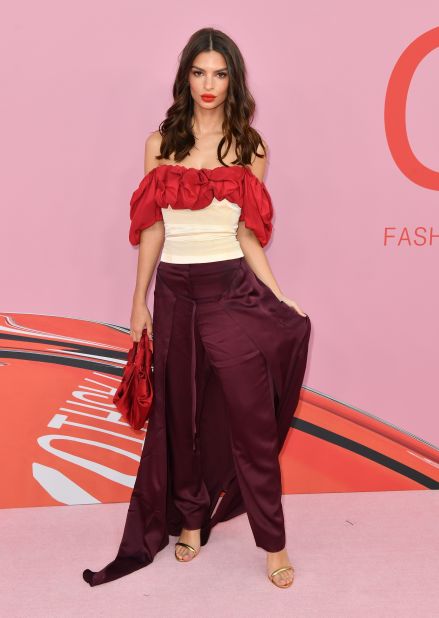 Emily Ratajkowski stunned in a ruffled top and maroon cape pants by Hellessy.
