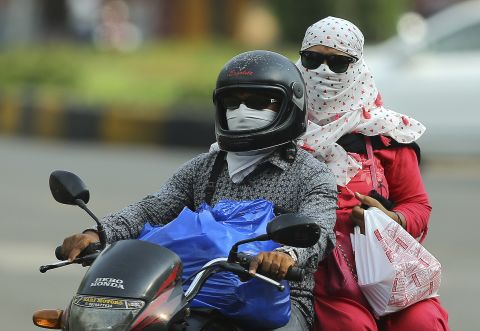 Commuters cover their faces with clothes to protect themselves from sun on a hot summer day in Hyderabad on Monday, June 3.