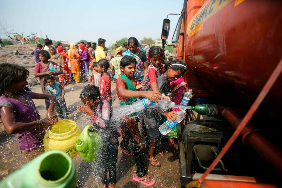People fill containers with water from a mobile tanker at a slum area on the outskirts of Jammu on Monday, June 3.