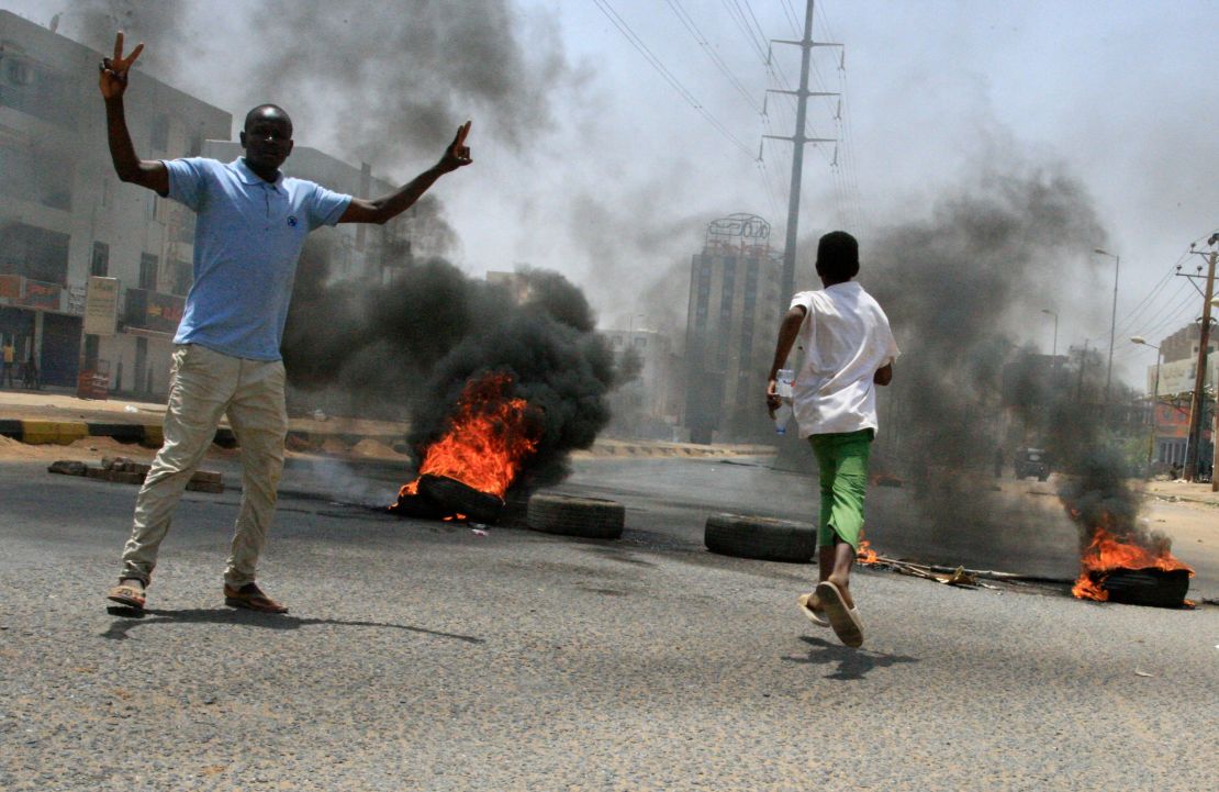 Sudanese protesters gesture as smoke billows from burning tyres near Khartoum's army headquarters on June 3.