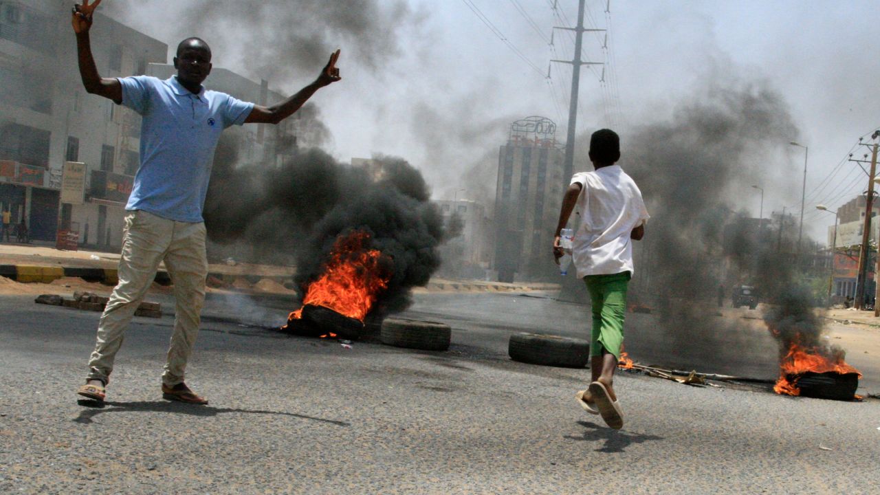 Sudanese protesters gesture as smoke billows from burning tyres near Khartoum's army headquarters on June 3.