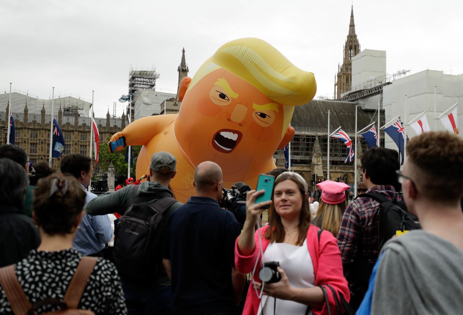 A woman takes a selfie as the "Trump Baby" blimp is inflated in Parliament Square.