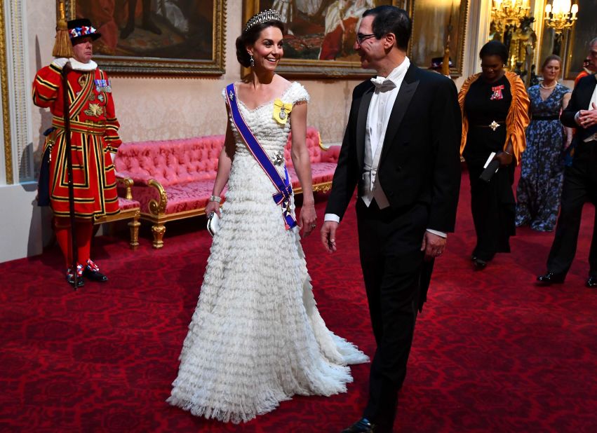 Catherine, Duchess of Cambridge, walking with US Secretary of Treasury Steven Mnuchin, wears a gown designed by Sarah Burton for Alexander McQueen, and the Lover's Knot tiara.
