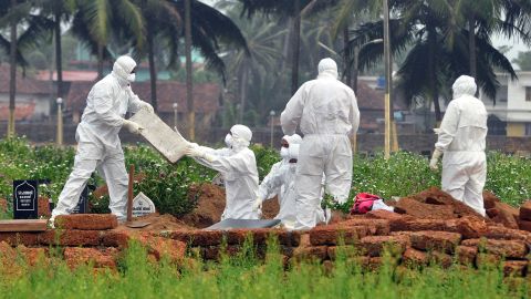 Doctors and relatives wearing protective gear dig a grave to bury the body of a Nipah virus victim on May 24, 2018.
