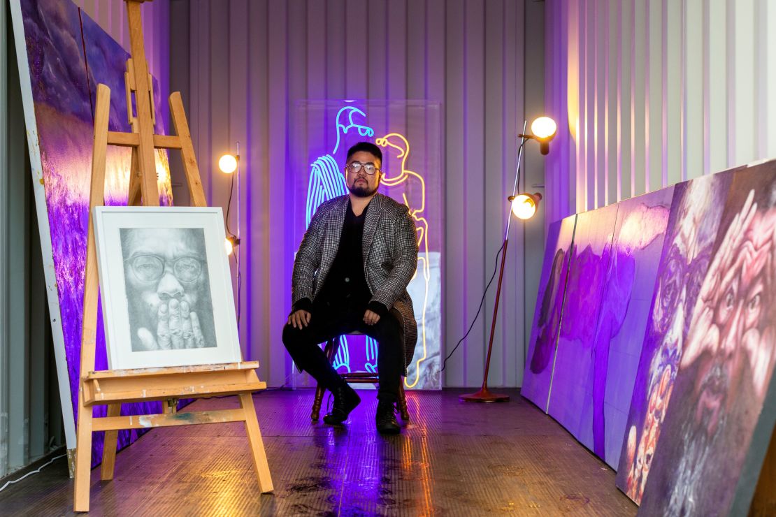 This picture taken on May 28, 2019 shows Chinese cartoonist Badiucao standing behind his artwork titled 'Light' in his studio in Melbourne.