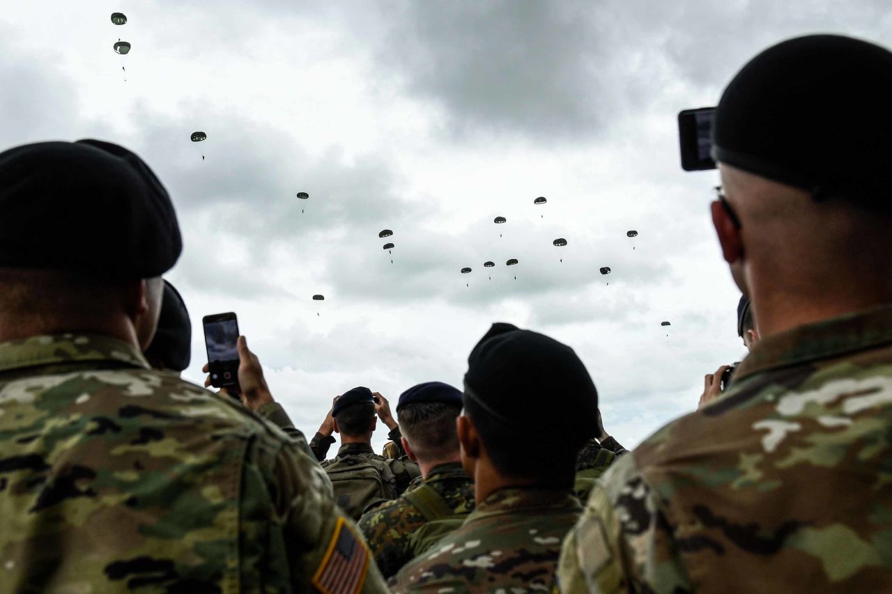 US soldiers take pictures of paratroopers dropping over Carentan in northwestern France as part of D-Day commemorations on June 5.