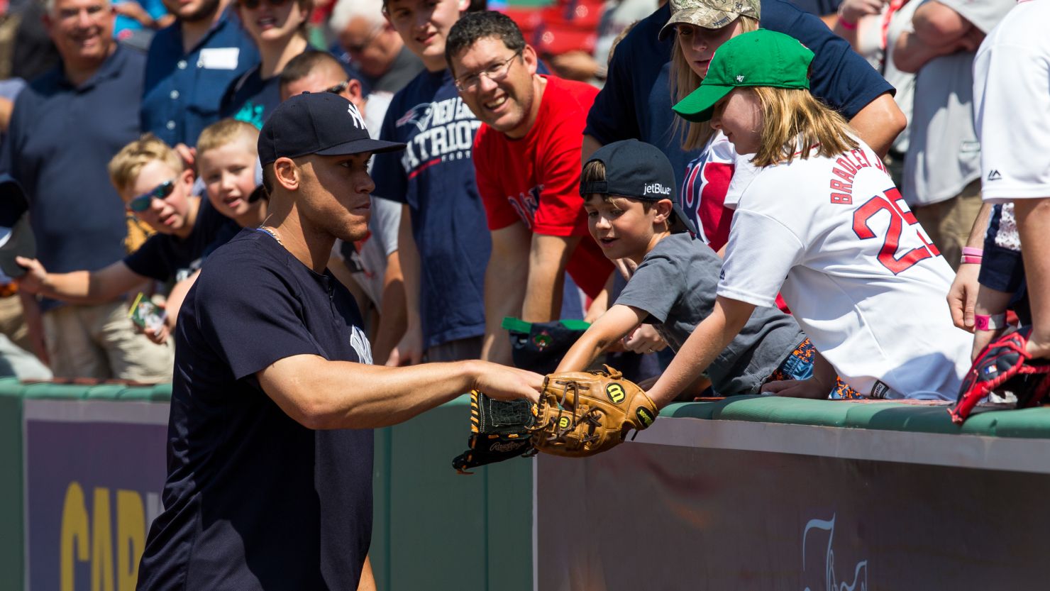 Aaron Judge #99 of the New York Yankees gives a ball to a young fan before a game against the Boston Red Sox at Fenway Park in July 2017
