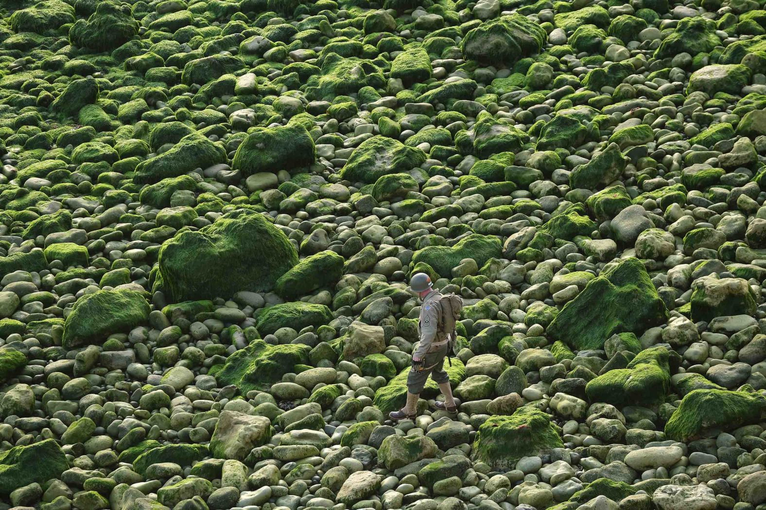 A US Army Ranger in the uniform of a World War II Ranger walks along rocks below La Pointe du Hoc before scaling cliffs in a re-enactment of the D-Day assault near Cricqueville-en-Bessin, France, on June 5.