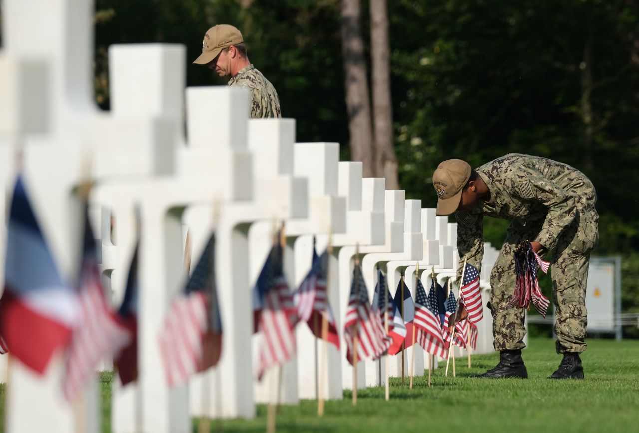 Members of the US Navy plant American and French flags at soldiers' graves at the Normandy American Cemetery near Colleville-Sur-Mer, France, on June 5.
