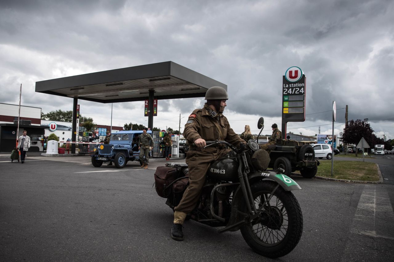 World War II enthusiasts in period vehicles pass through a fueling station in Port-en-Bessin in northwestern France's Normandy on June 5.