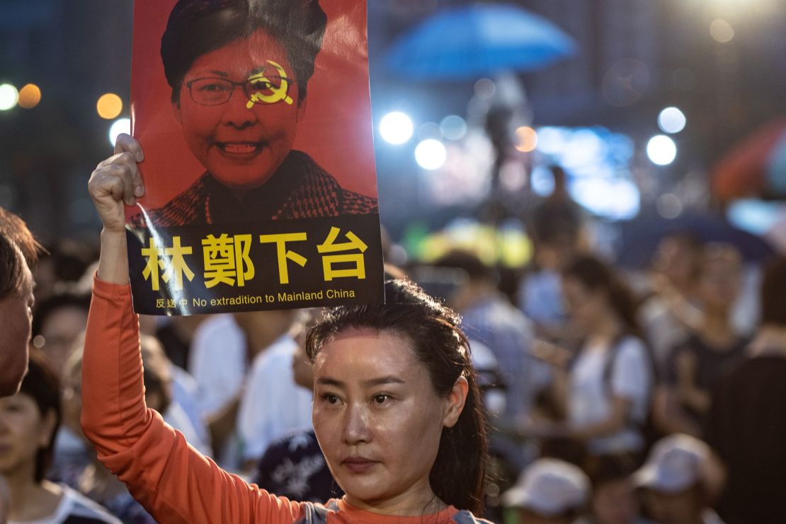 A woman holds a poster of Hong Kong Chief Executive Carrie Lam, against a proposed extradition law, before a candlelight vigil at Victoria Park in Hong Kong on June 4, 2019.