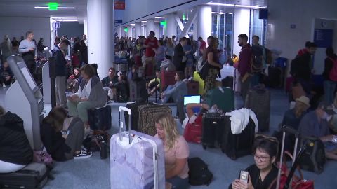 Passengers wait in a darkened Los Angeles International Airport on Wednesday night.