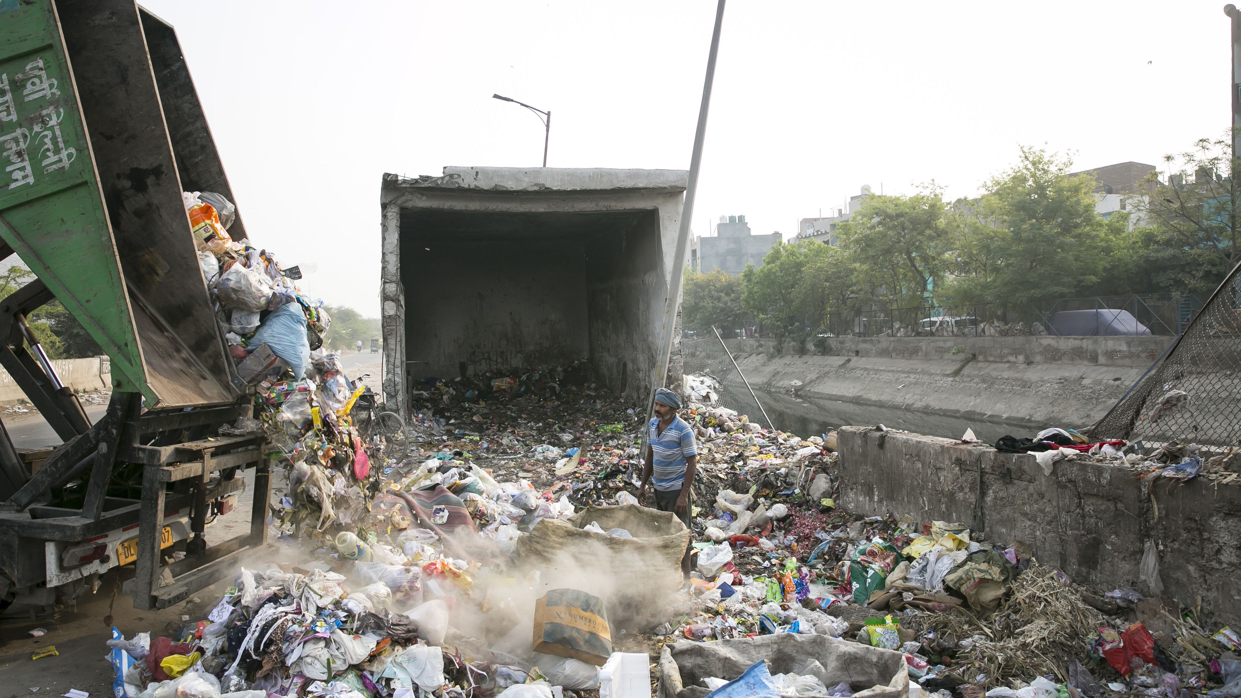 An Indian worker watches a truck dump trash for sorting in New Delhi in April 2019.