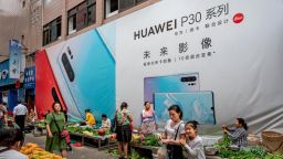 MANGSHI, CHINA - JUNE 1: A woman shops with her daughter in front of a billboard advertising smartphones for China's Huawei Technologies Co., at a market on June 1, 2019 in Mangshi, Yunnan Province, southwestern China. (Photo by Kevin Frayer/Getty Images)