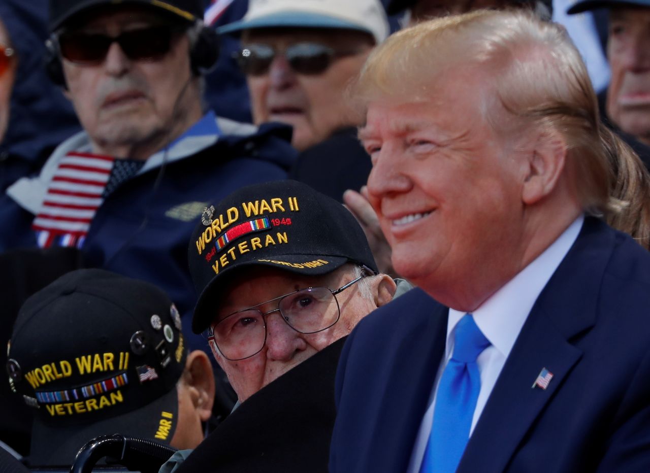 A World War II veteran looks over Trump's shoulder during the commemoration ceremony.