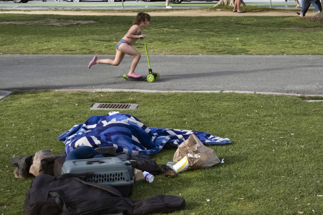 A child rides her scooter past a homeless person in Santa Monica on June 3.