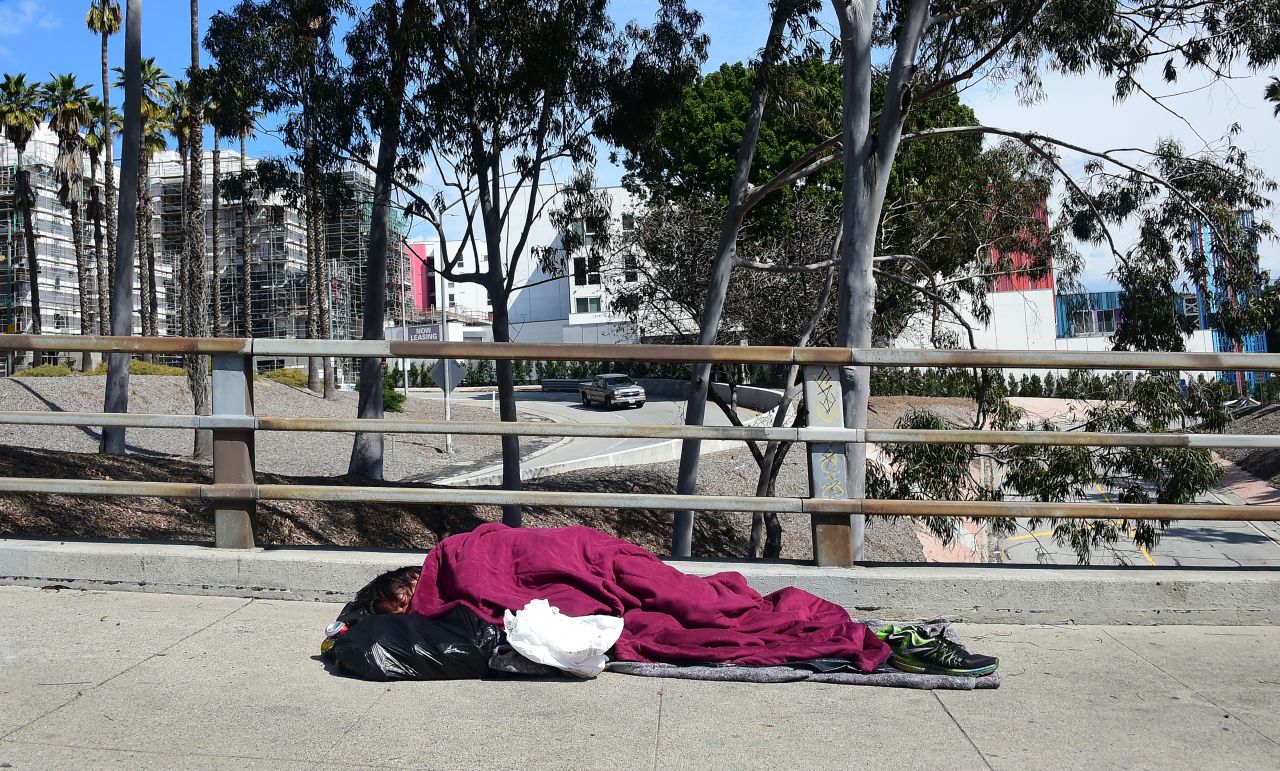 A homeless man sleeps on a sidewalk in Los Angeles on March 10.