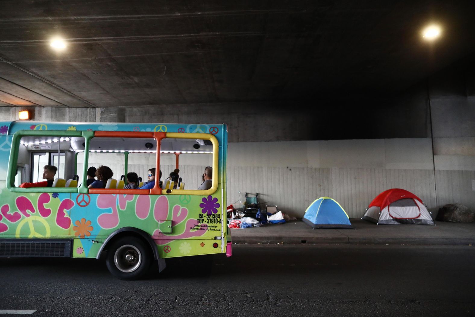 A tour bus passes a homeless encampment located beneath an overpass on June 5.