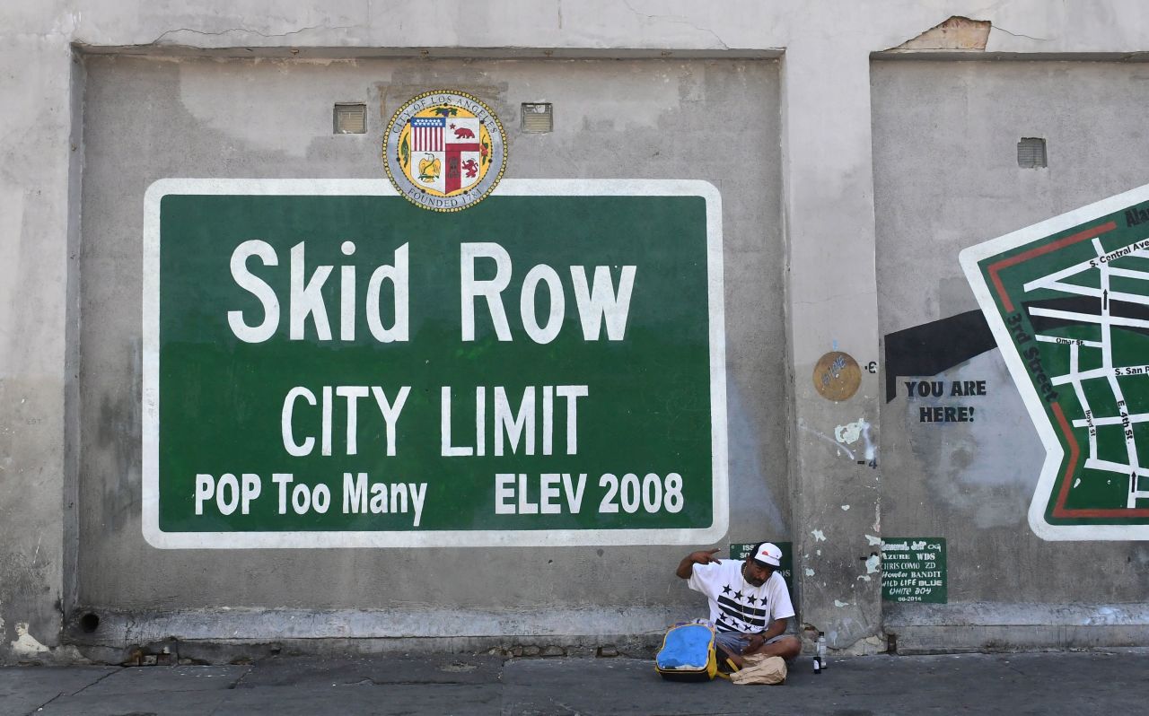 A man gestures while seated beside a Skid Row painting on May 30.