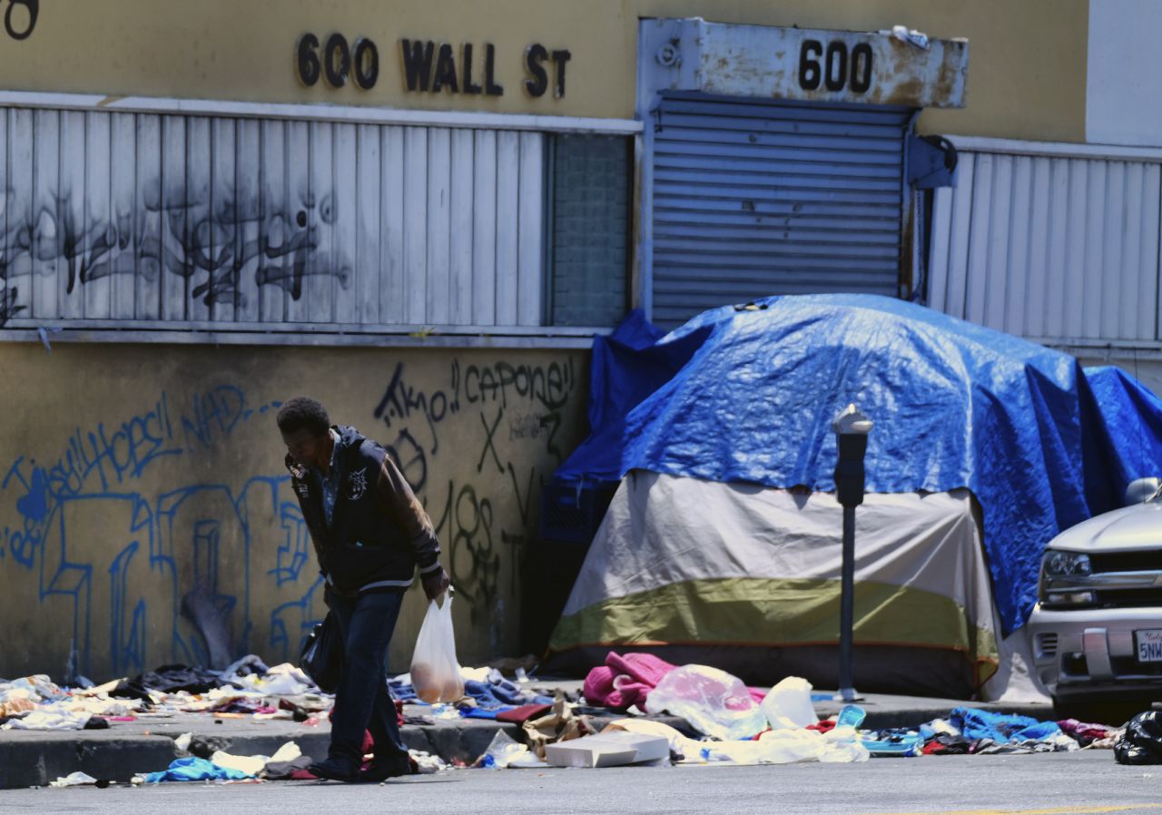 A homeless man walks along a street lined with trash across from a Los Angeles police station on May 30.