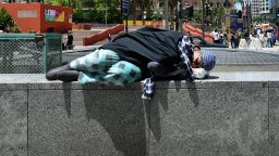 A pedestrian walks past a homeless person sleeping outdoors in downtown Los Angeles, California on May 24, 2019 where an increasing homeless population is reaching a crisis point. (Photo by Frederic J. BROWN / AFP)        (Photo credit should read FREDERIC J. BROWN/AFP/Getty Images)
