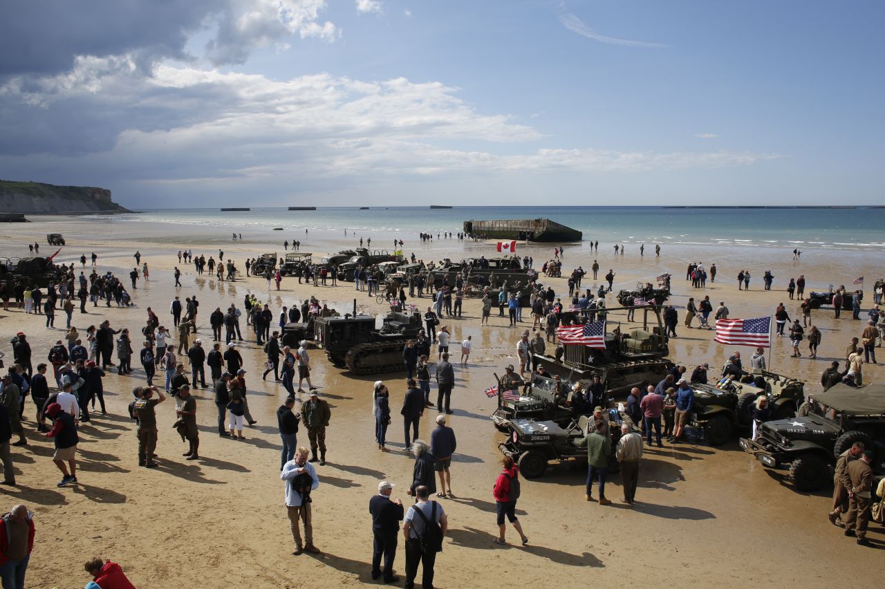 People walk among vintage World War II vehicles parked on the beach during events to mark the 75th anniversary of D-Day in Arromanches, Normandy, France, on Thursday, June 6, 2019. World leaders and veterans gathered Thursday in France to mark the 75th anniversary of the D-Day landings.